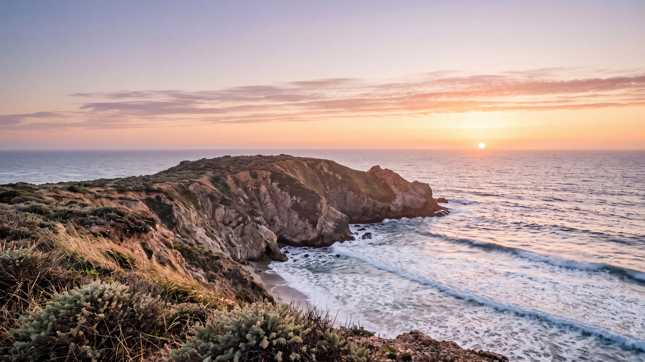 AI-created interpretation of Big Sur at sunset, with rugged coastal cliffs, foaming Pacific waves, and a coral and golden sky.