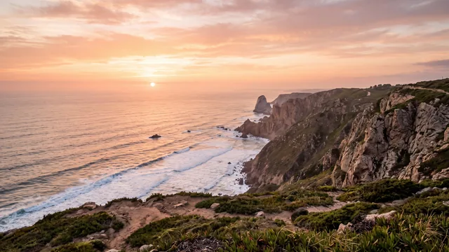 AI-created interpretation of Cabo da Roca on the Sintra coast of Portugal at sunset, with rugged cliffs, sea stacks, long white wave lines and coastal vegetation beneath a peach and amber sky.