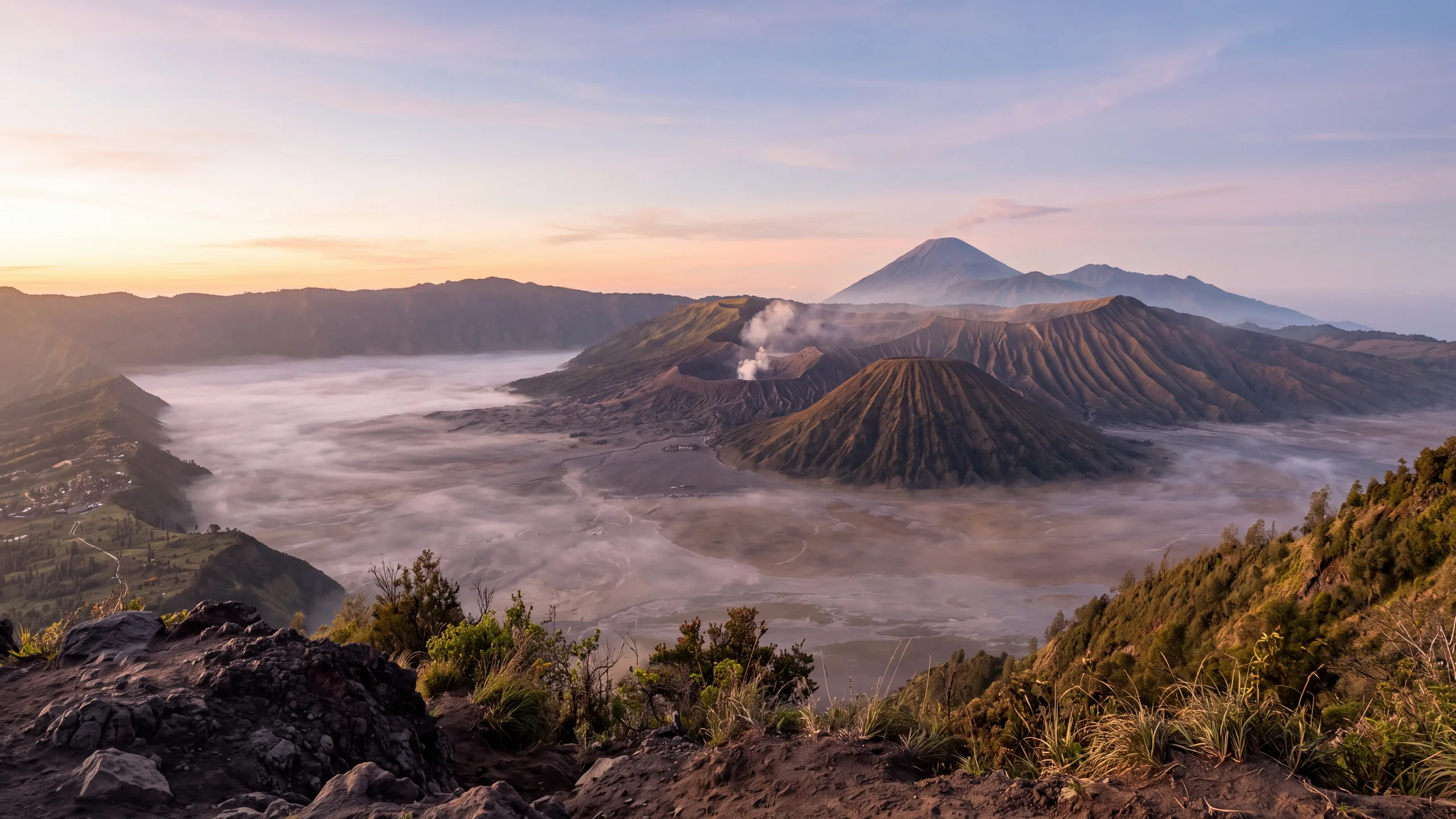 AI-created interpretation of Mount Bromo in East Java at sunrise, with a softly steaming crater, the ribbed cone of Mount Batok and distant volcanic slopes above a misty caldera.
